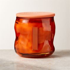 an orange glass jar sitting on top of a table