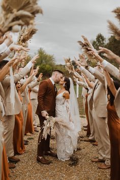 a bride and groom kissing in front of a group of people holding their hands up