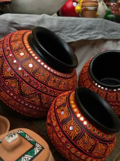 three colorful vases sitting on top of a wooden table next to other decorative items