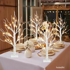 the table is set with white trees and plates