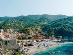 an aerial view of a beach with boats in the water and mountains in the background