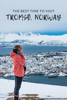 a woman standing on top of a snow covered hill looking out at the city below