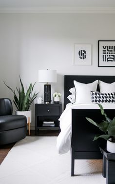 a black and white bedroom with plants on the nightstands in front of the bed