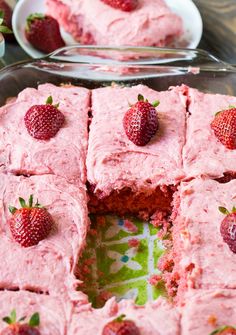 there is a cake with pink frosting and strawberries on the top, cut into squares