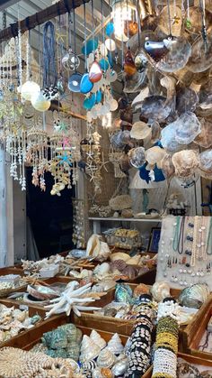 an assortment of jewelry and necklaces in a market stall with lots of hanging items