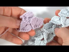 two hands are holding crocheted pieces of yarn