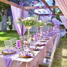 a long table with purple and white decorations on the top is set for a party