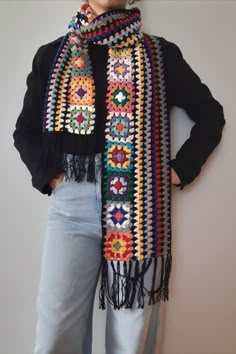 a woman is wearing a colorful crochet scarf