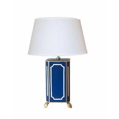 a blue and gold table lamp with a white shade on the top, against a white background