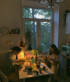 two people sitting at a table in front of a window