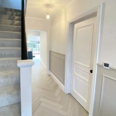 an empty hallway with white walls and stairs