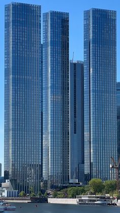 three tall buildings are next to each other on the water in front of some boats