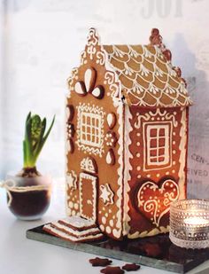 a gingerbread house is sitting on a table next to a potted succulent