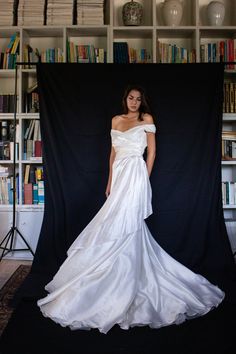 a woman in a white wedding dress standing next to a bookshelf