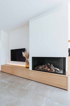 a modern fireplace in the middle of a living room with white walls and flooring