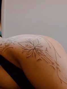 a woman with tattoos on her back laying down