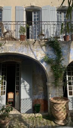 an old building with blue shutters and potted plants on the balconies