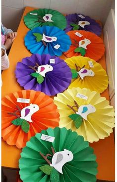 colorful paper fans with birds on them are sitting on an orange table in front of a child's room