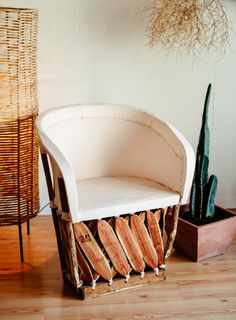 a white chair sitting on top of a wooden floor next to a potted plant