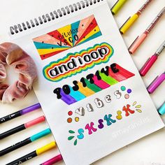 a spiral notebook with some writing on it next to crayons and pencils