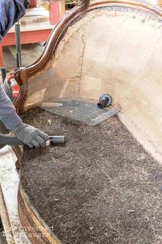 a man is working on an old couch with wood shavings and metal grates