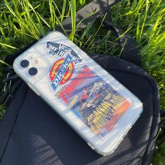 an iphone case sitting on top of a black bag in the middle of some grass