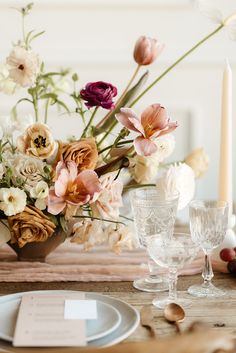 an arrangement of flowers and candles on a table