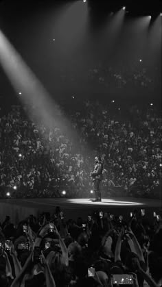 a man standing on top of a stage in front of a crowd at a concert