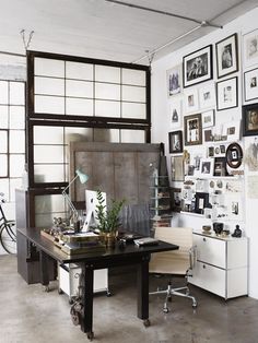 an office with lots of pictures on the wall and desks in front of it