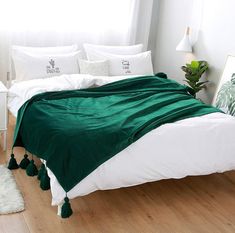 a bed with white sheets and green blankets