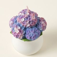 a white vase filled with purple and blue flowers