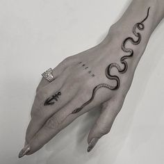 a woman's hand with a snake tattoo on it