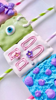 three decorated birthday candles sitting on top of a white table with purple and green frosting