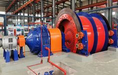 a large machine that is inside of a building with orange and blue pipes on the floor