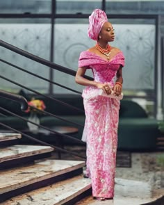 a woman in a pink dress is standing on some steps and looking off to the side