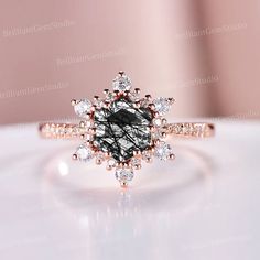 an engagement ring with a black and white diamond in the center, on top of a table