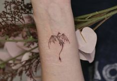 a small dragon tattoo on the wrist and arm, with flowers in the back ground