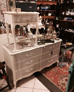 an old dresser with glassware on it in a room full of other furniture and antiques