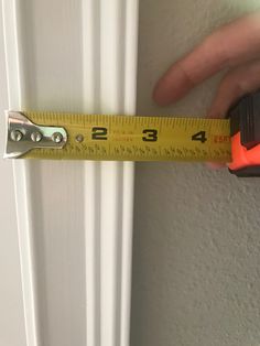 a person holding a tape measure in front of a door with their hand on the handle