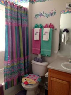 a bathroom with a toilet, sink and colorful shower curtain in it's corner