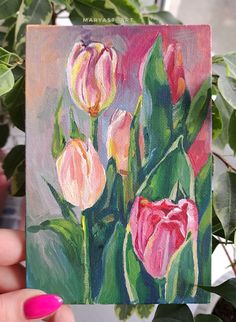 a painting of pink tulips is being held up by a woman's hand