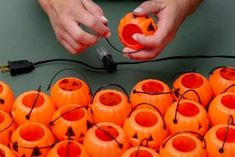 a person holding an orange object over many pumpkins with wires attached to the ends