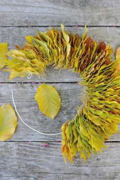 a wreath made out of dried leaves on top of a wooden table next to a string