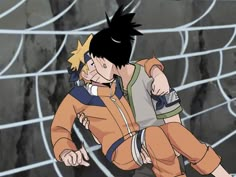 two young men hugging each other in front of a soccer net with rocks behind them