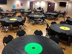 an empty room with tables and chairs covered in black tablecloths, green circles on top