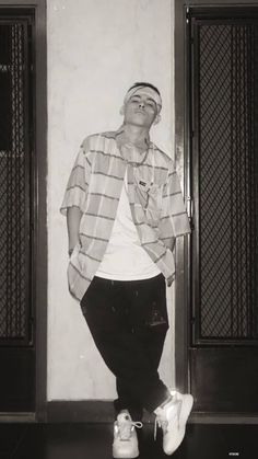 black and white photograph of a man standing in front of two doors with shoes on the floor