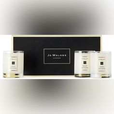 three candles sitting in front of a black box with the name jo malone on it