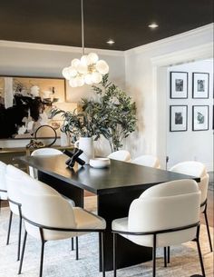 a dining room table with white chairs and a black centerpiece on top of it