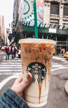 someone holding up a starbucks drink in the street