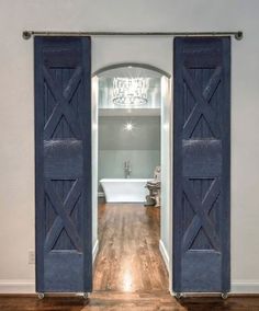 an open door leading to a bathroom with a tub and chandelier in the background